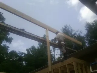 Carpenter setting a ridge beam over a new addition frame — Ice Dam Removal by Roofing Brothers in Crozet