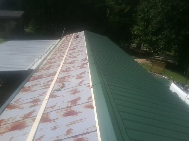 Old rusted panels beside newly installed green metal roofing — Wind Damage Roof Repair by Roofing Brothers in Crozet