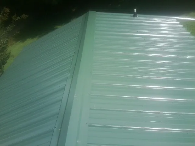 New green metal panels meeting at the ridge of a roof — Flat Roof Repair work by our crew in Crozet