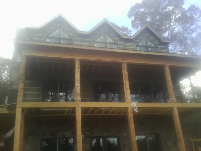 Dormers and porch framing on a large log home under construction — Roof Coating work by our crew in Crozet