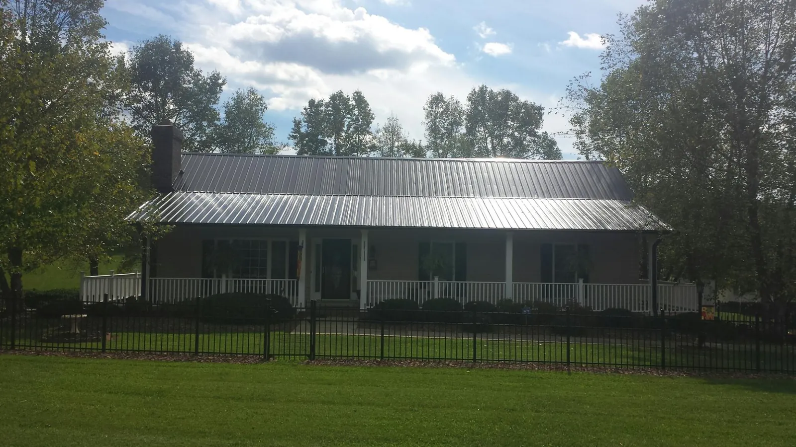 Gray metal roof on a brick ranch with a full width front porch — Gutter Guard Installation work by our crew in Crozet