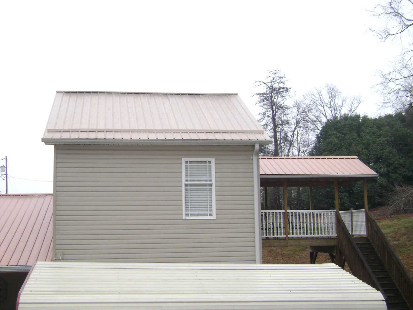 Tan metal roofs on a two story addition and attached porch, from a Roof Replacement job in Crozet