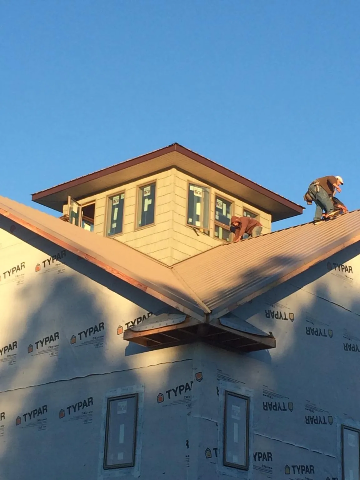 Roofers working around a rooftop cupola on a new metal roof at sunset — Roof Waterproofing in Crozet by Roofing Brothers